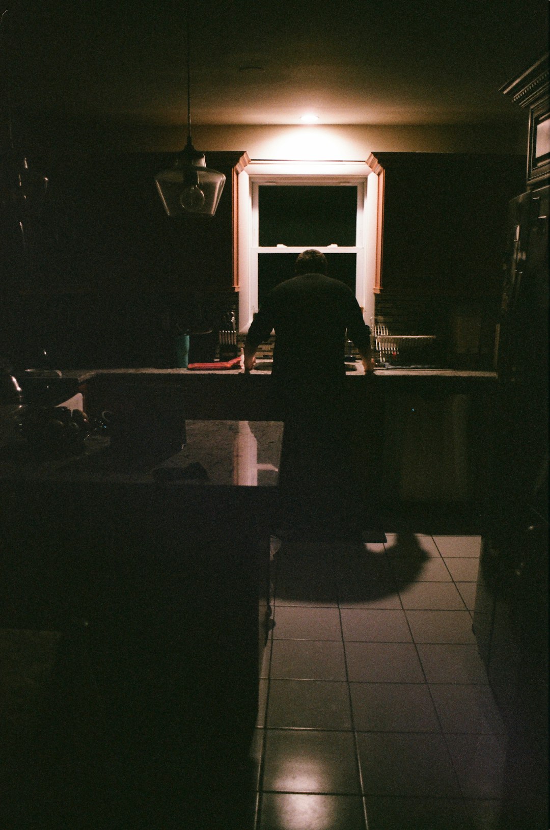 a-person-stands-in-a-dimly-lit-kitchen-qkpvnxql1-m